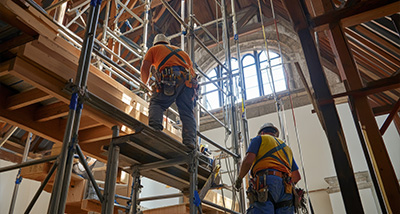 construction workers on scaffolding working on a building under renovation with natural light streaming in showcasing modern tools and equipment