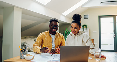two people collaborating on laptop in modern workspace featuring papers and creative ideas about 10 projects
