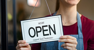 a person holding an open sign promoting support for local businesses inviting customers to visit the store four local options available
