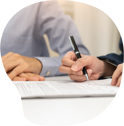 person signing a document with another individual holding a pen and paperwork discussing two important points